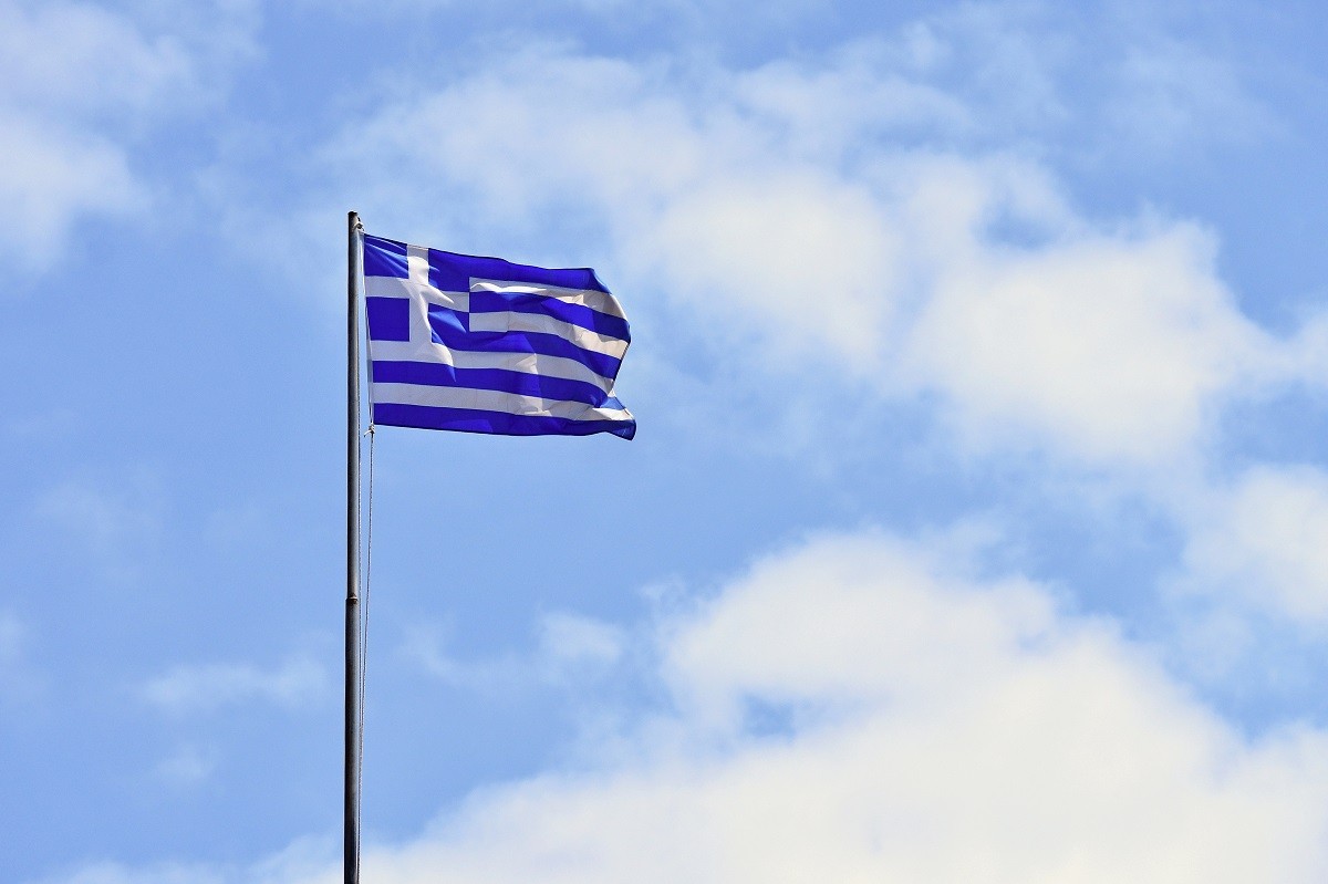 Flag of Greece Flying in Wind and Blue Sky. Summer background for travel and holidays. Greece Crete.