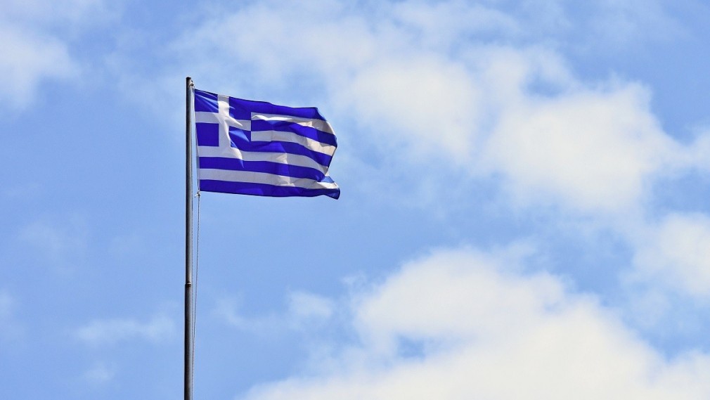 Flag of Greece Flying in Wind and Blue Sky. Summer background for travel and holidays. Greece Crete.